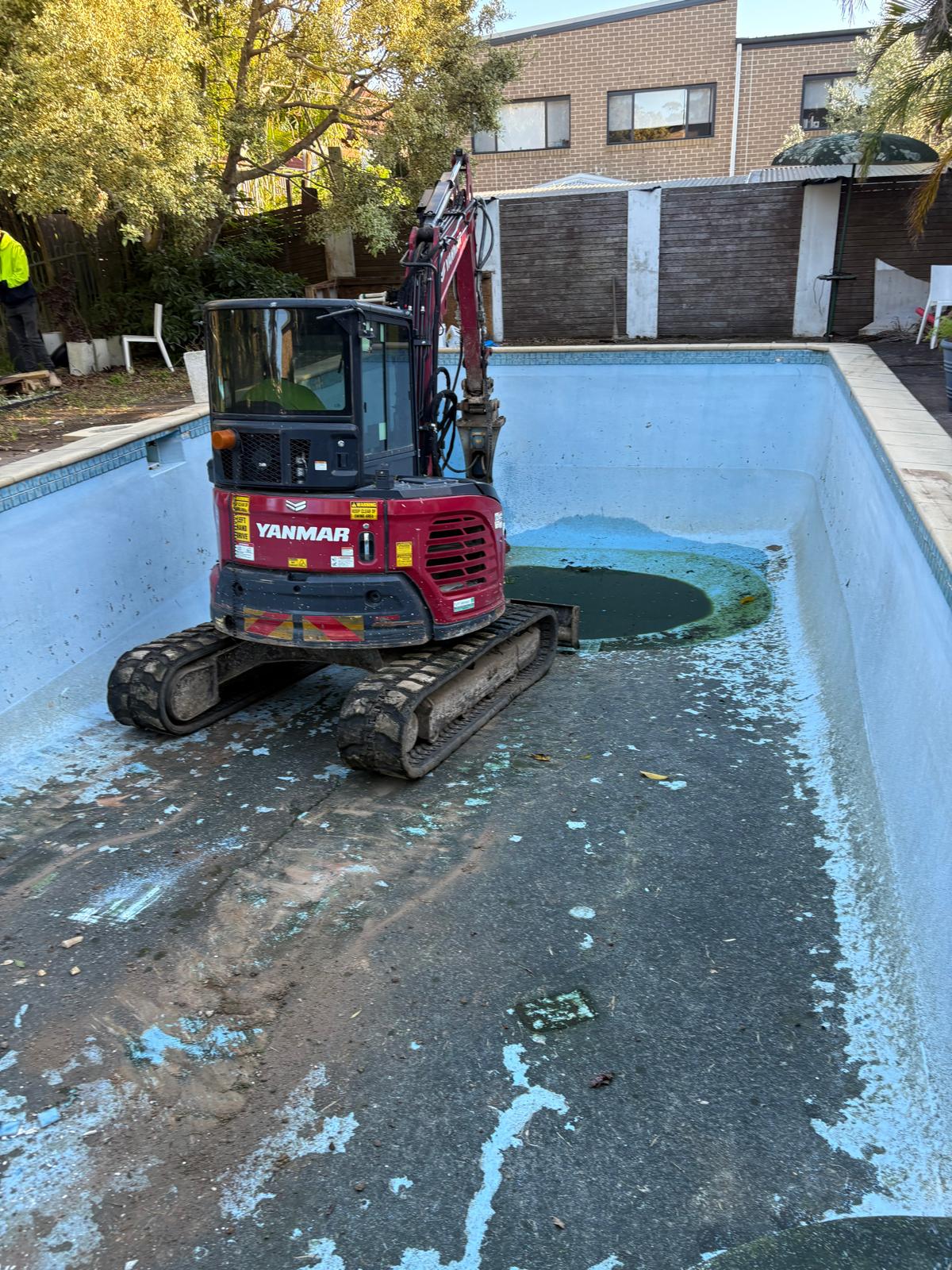 Excavator removing a concrete swimming pool
